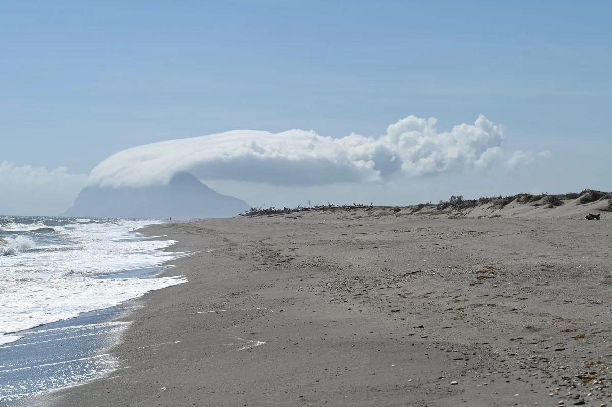 The Rock of Gibraltar seen from a beach near Sotogrande, almost hidden under a thick white Levanter cloud streaming westward from its summit