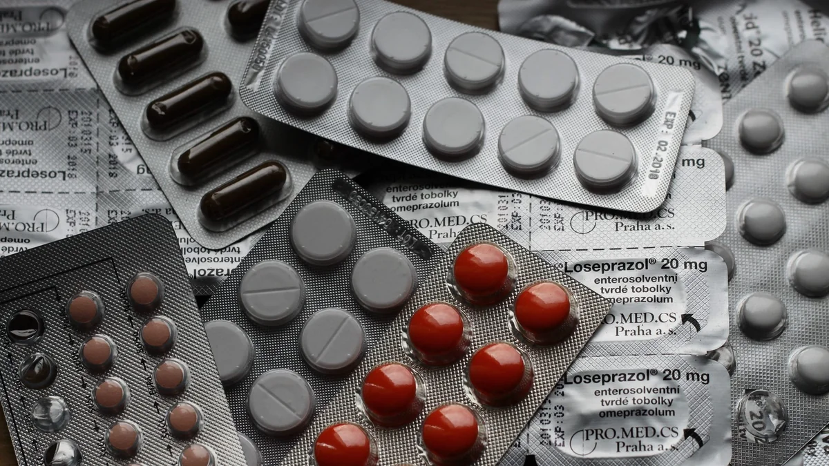 Several blister packs of tablets and capsules piled on a table