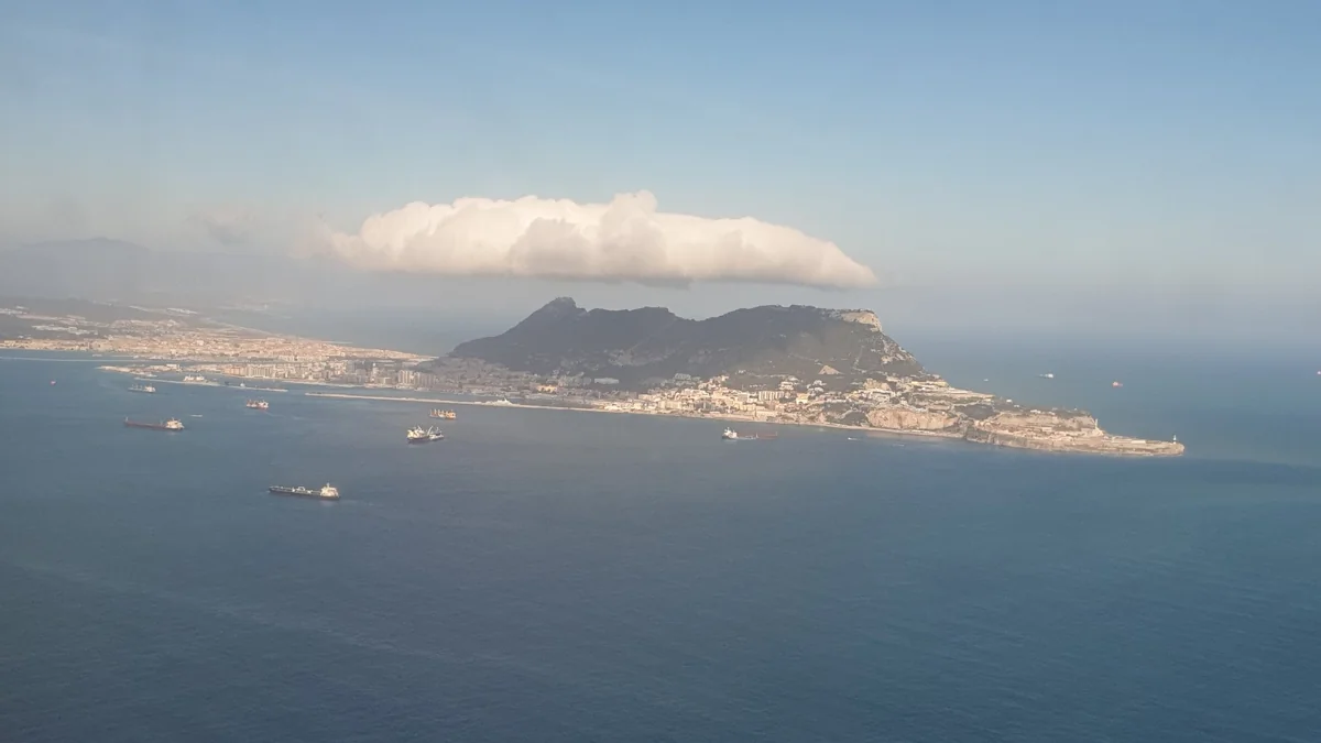 Aerial view of the Rock of Gibraltar with a long white Levanter cloud above it and ships anchored in the bay