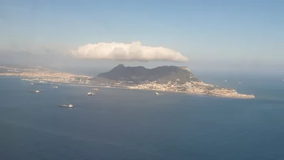 Vista aérea del Peñón de Gibraltar con una larga nube blanca de levante encima y barcos fondeados en la bahía