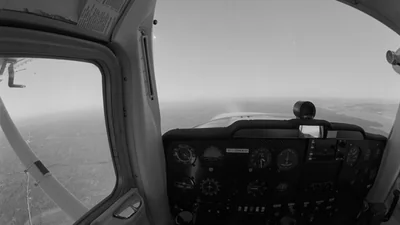 Vista desde la cabina de un Cessna 150, por encima del panel de instrumentos, hacia un horizonte con calima sin una línea clara entre tierra y cielo
