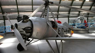 Un autogiro Cierva C.19 plateado, con su rotor y su hélice, expuesto en un hangar del Museo de Aeronáutica y Astronáutica de Cuatro Vientos, Madrid