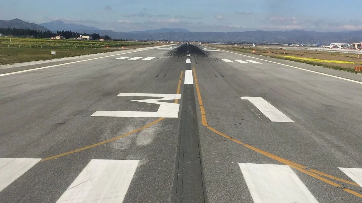 Runway designator 13 and threshold markings at Málaga-Costa del Sol Airport, seen from the runway with mountains in the distance