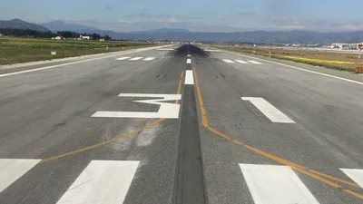 Runway designator 13 and threshold markings at Málaga-Costa del Sol Airport, seen from the runway with mountains in the distance