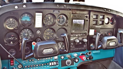 El panel de instrumentos y los cuernos de mando de un Cessna 172, con instrumentos de vuelo analógicos y la pila de radios