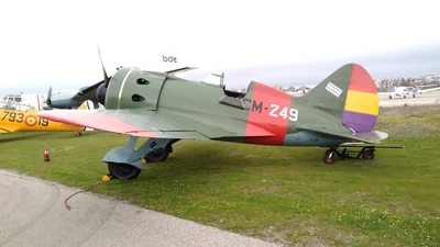 Caza Polikarpov I-16 verde con distintivos republicanos y el código CM-249 sobre la hierba en una exhibición de la Fundación Infante de Orleans, con un avión amarillo detrás
